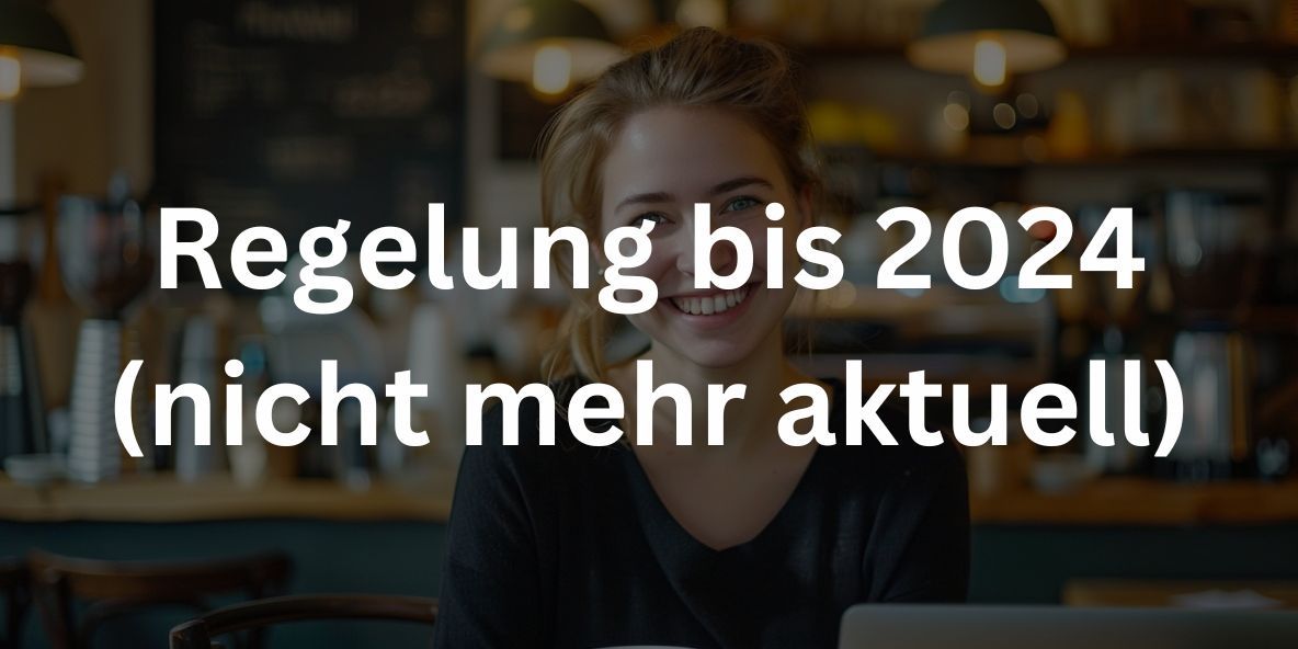 Junge Unternehmerin lächelt in die Kamera, sitzt mit Laptop und Kaffee an einem schicken, modernen Tisch in einem minimalistischen Café.