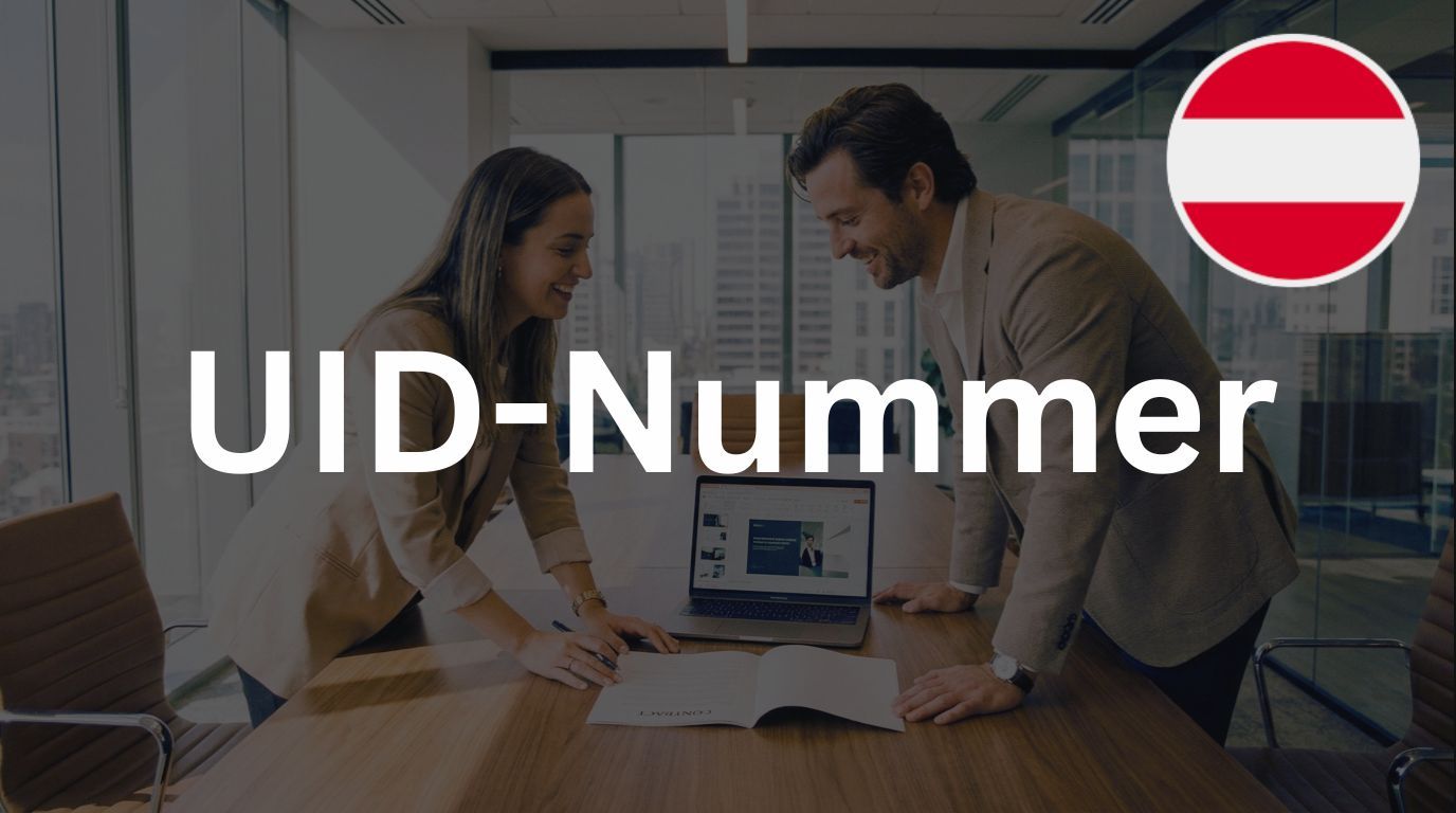 Zwei Personen besprechen ein Dokument am Konferenztisch neben einem Laptop in modernem Büro, darüber der Wortlaut 'UID-Nummer' und österreichische Flagge.